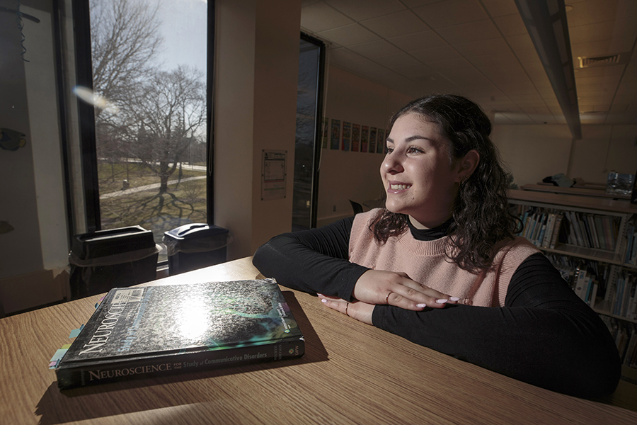 A student sits at a table with a book titled Neuroscience in front of her.