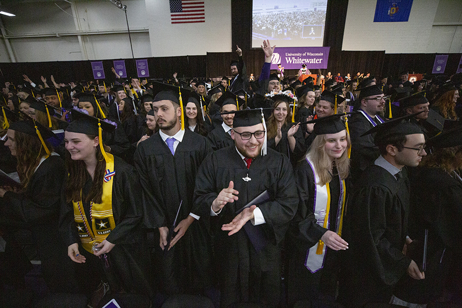 Graduates in their caps and gowns clap during the ceremony.