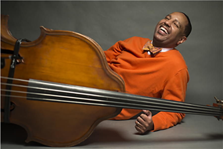 Man laughing, holding a cello.
