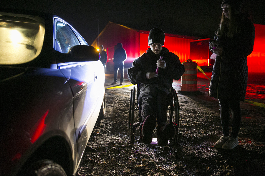 A student is outside in the dark next to a car during a crime scene simulation.