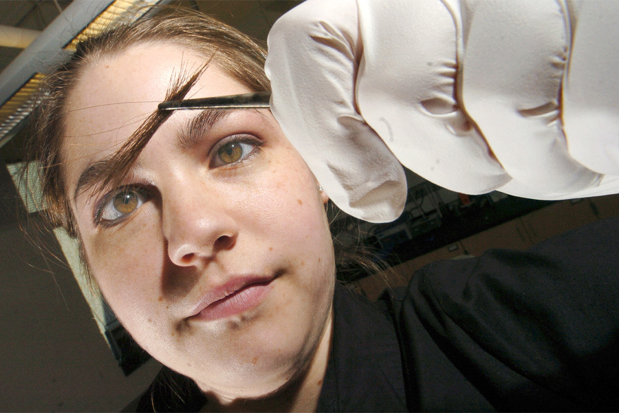 A student inspects hair in a tweezers.