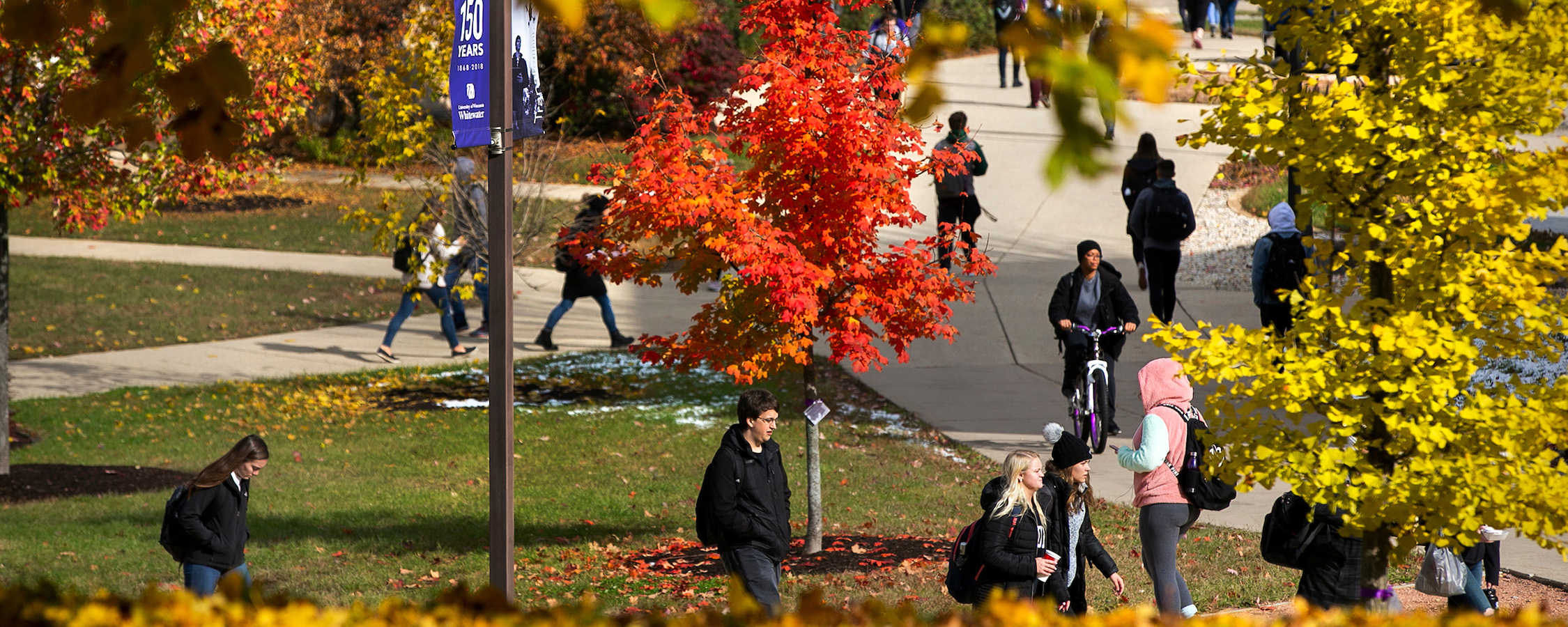 Group of students walking on UW-Whitewater campus with red and yellow trees around them