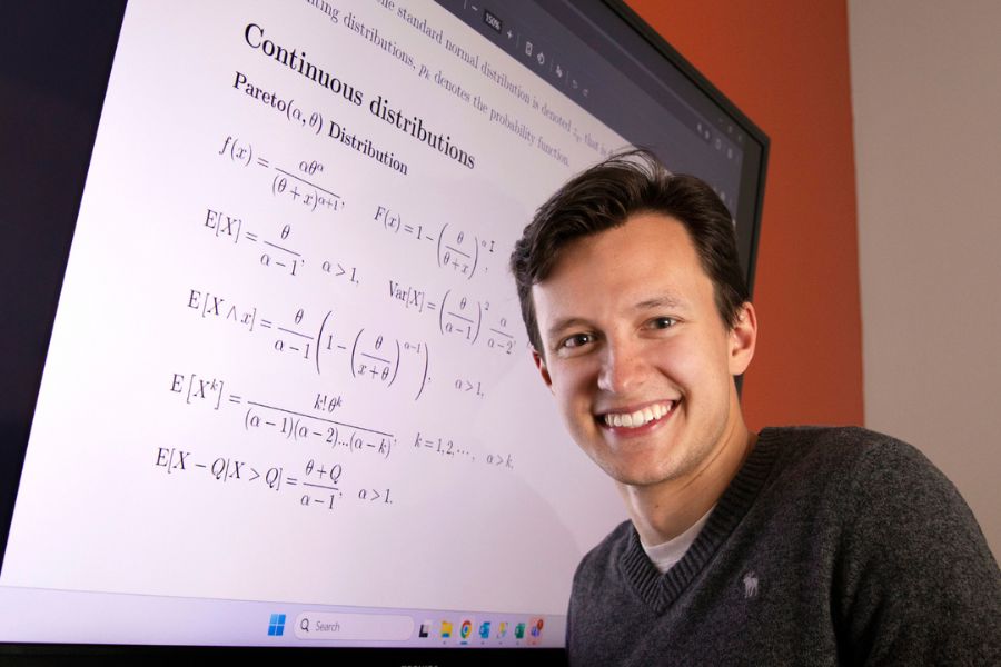 Chris smiles at the camera with a board behind him.