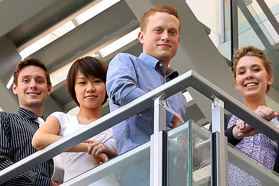 Image: 4 graduate students posing on balcony.