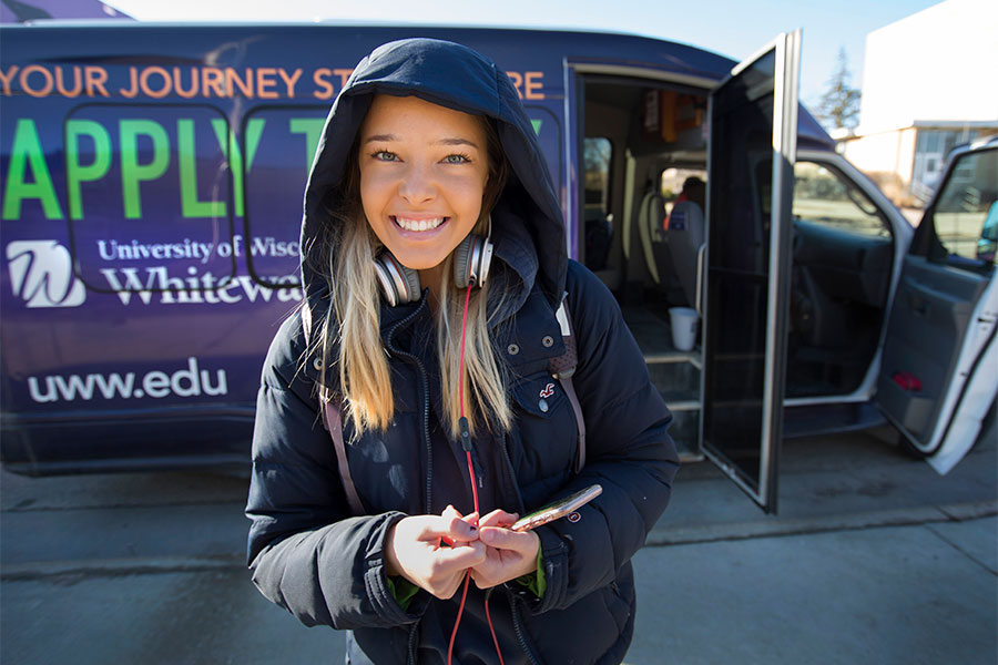 A student stands outside by the purple shuttle.