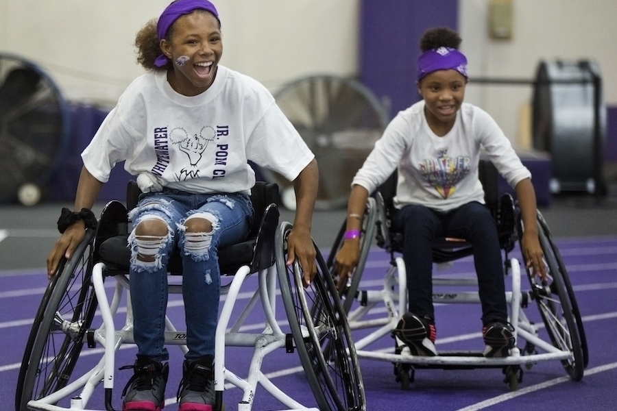 Image of two teenage girls playing wheelchair basket ball at Family Fest.