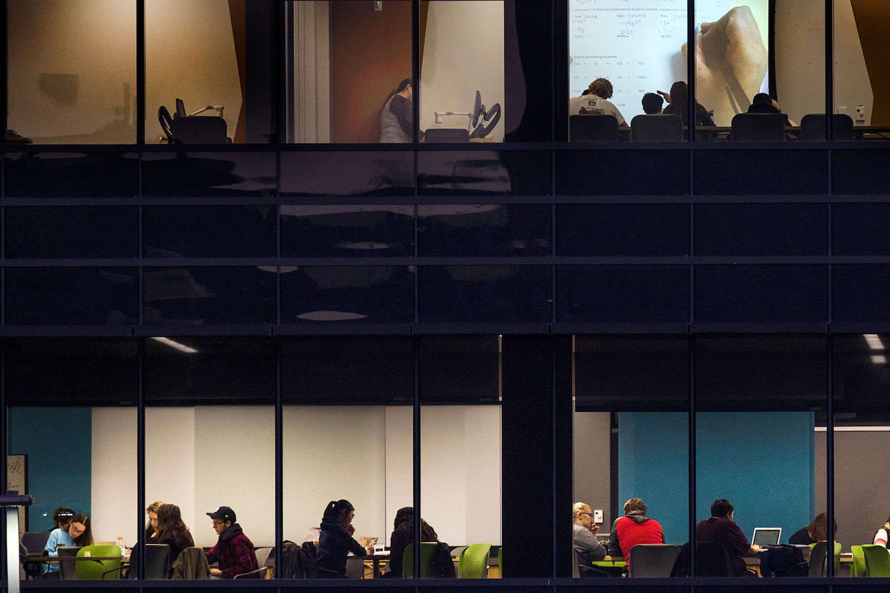 The Success Center at night. Students collaborate at tables and use a projector.