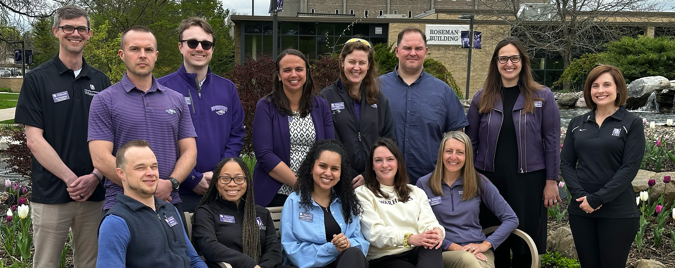 Group of people, advisors at UW-Whitewater stand together in front of the building that houses their office