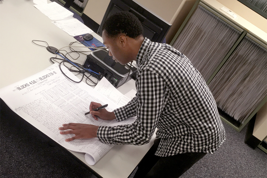 A person leans over a large sheet of paper in the Milwaukee County Deeds Office.