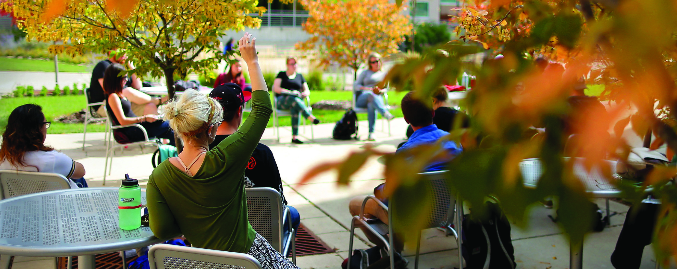 A class is held outside amidst fall leaves.