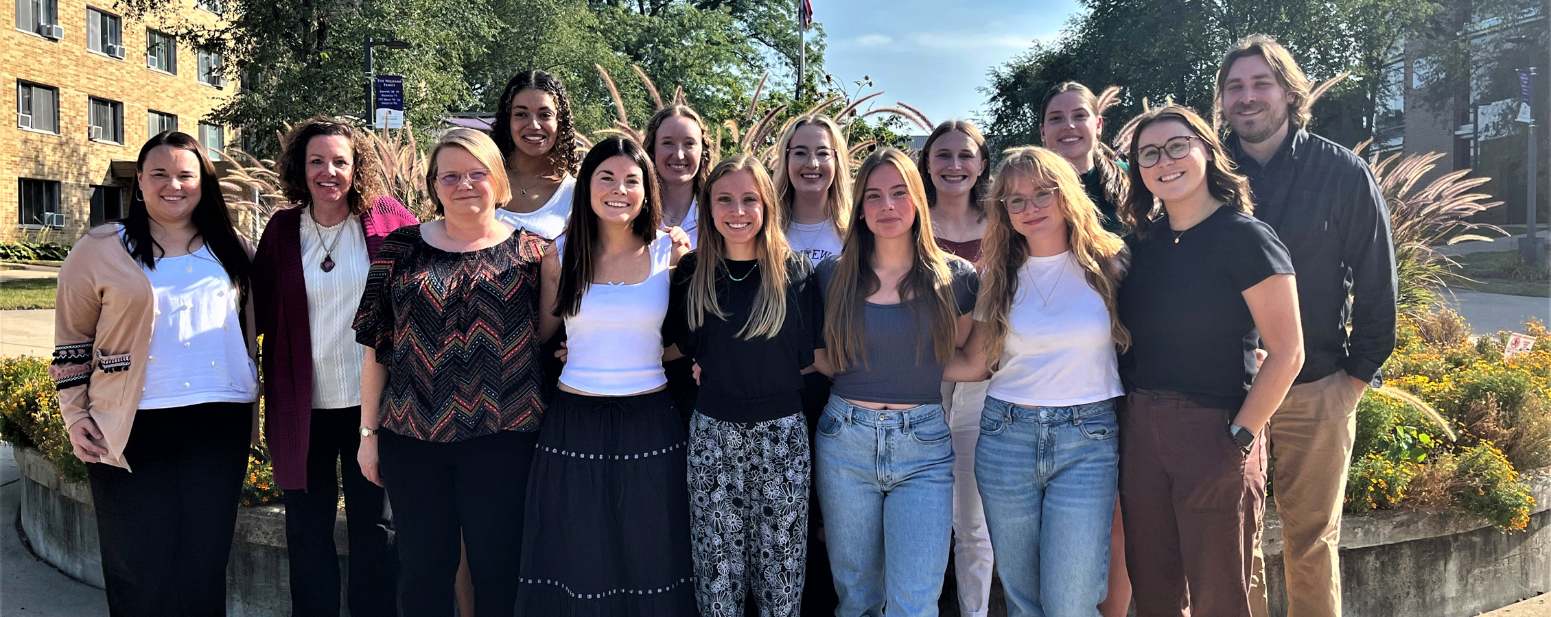 A group photo of the current school psychology students stand outside and smile at the camera.