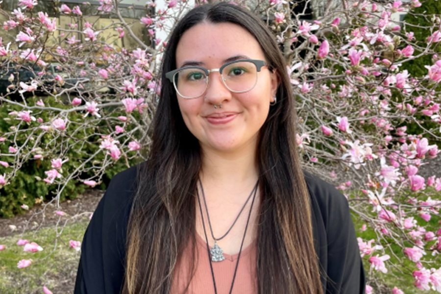 Krystalyn Terski stands outside in front of a tree with white and pink blossoms.