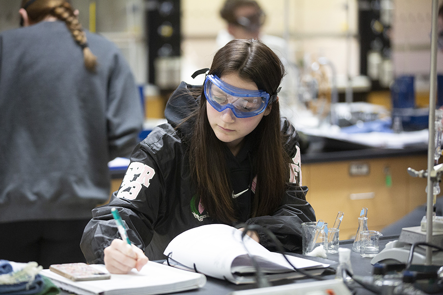 A student works in a lab while wearing safety glasses.