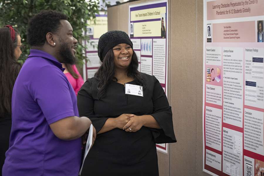 Two King/Chavez scholar students look at a large poster during Undergraduate Research.