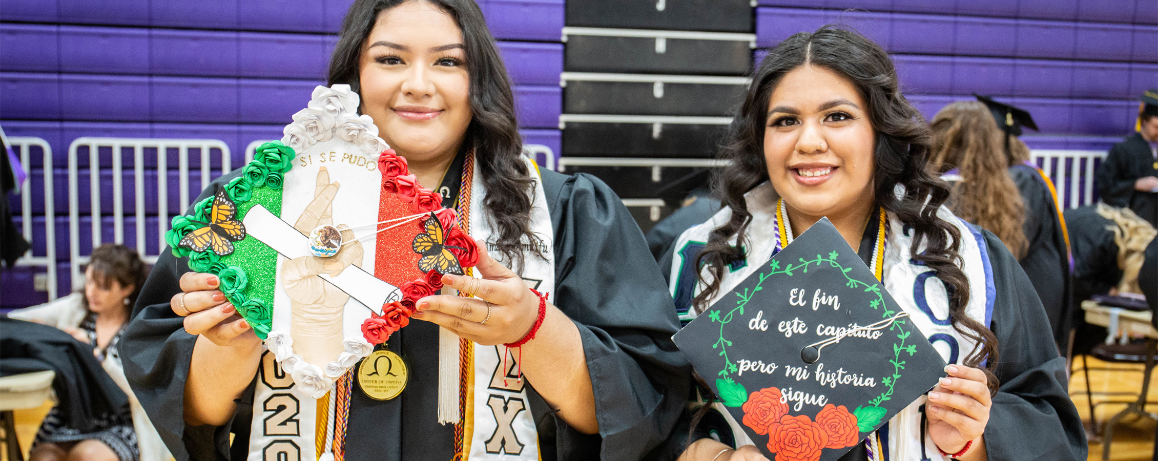 Two Spanish majors at graduation show their decorated caps.