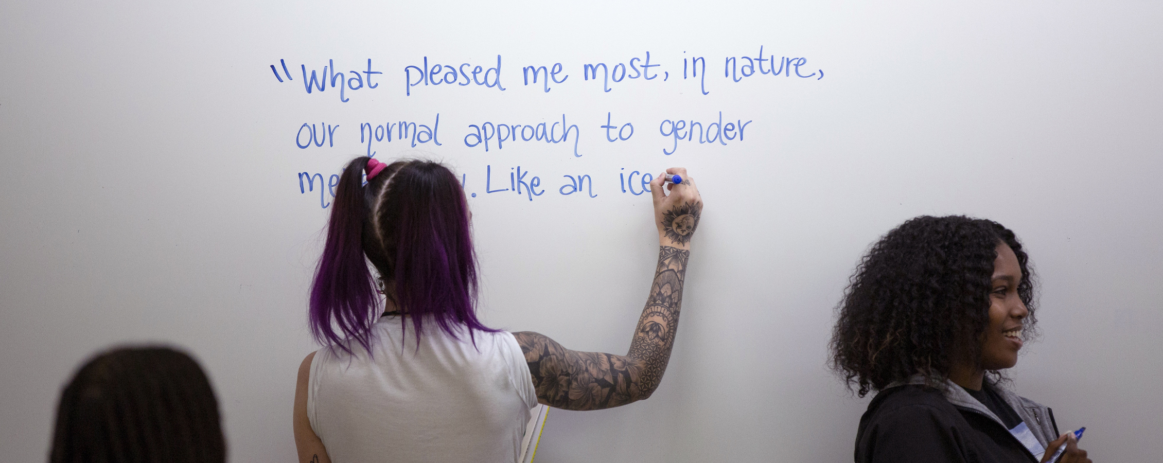 A person writes a quote on a whiteboard.