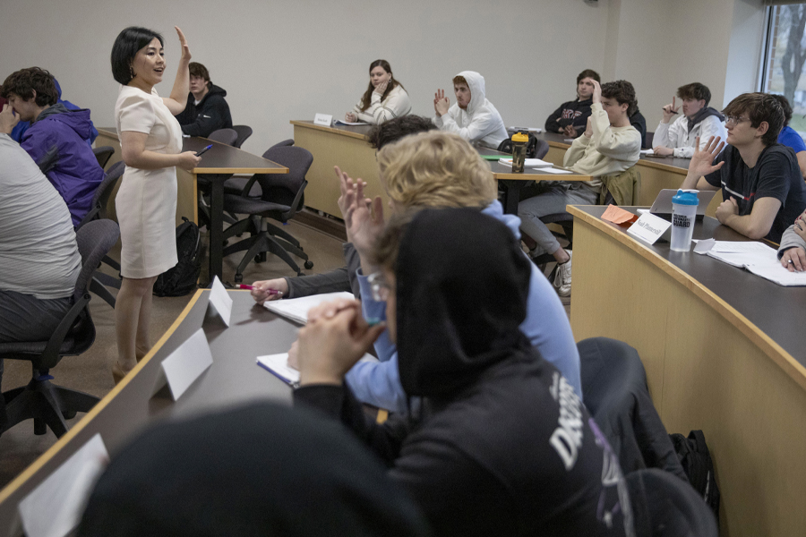 A faculty member teaches in class and raises her hand.