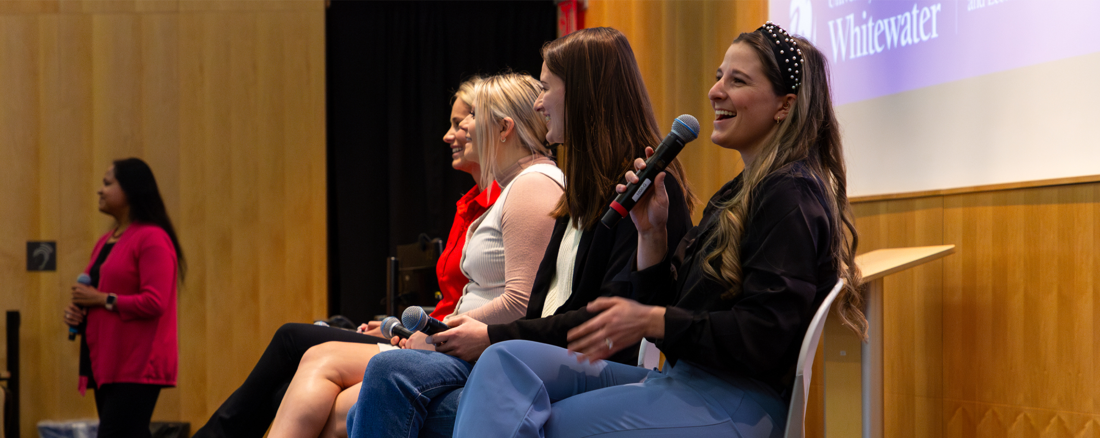 A panel of young females speak at the front of Timmerman Auditorium.