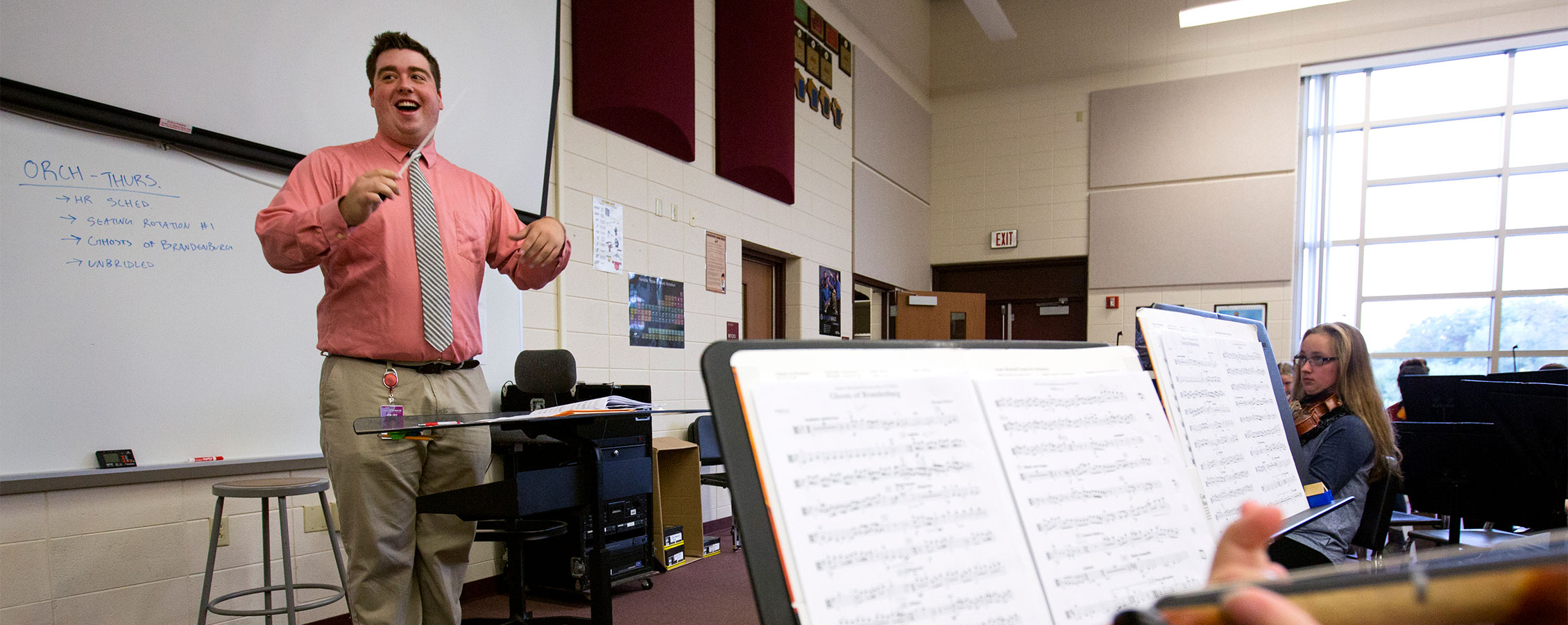 Middle school music teacher conducts band members.