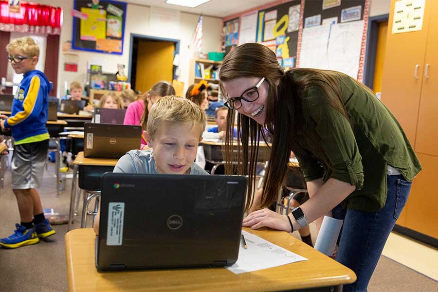 Early childhood teacher helping student with computer