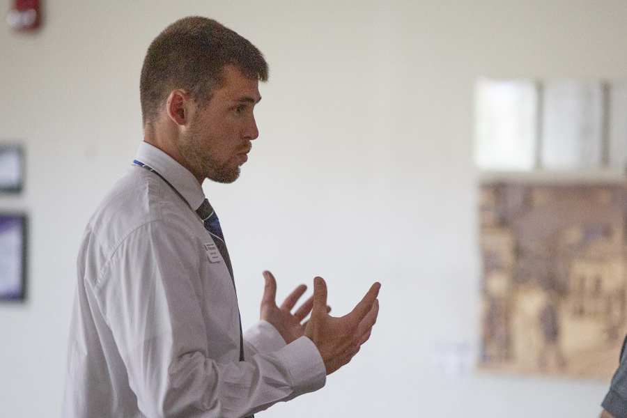 A person wearing a white collar shirt and tie speaks with their hands.