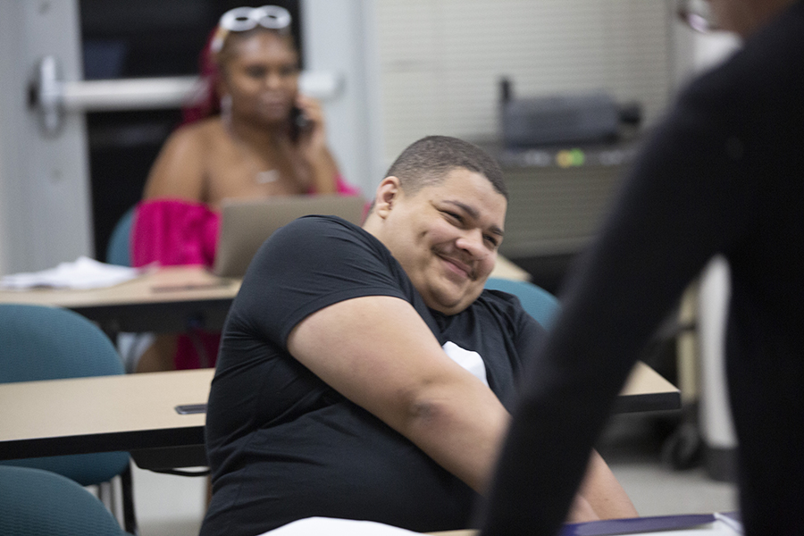 A student sits in class, smiling.