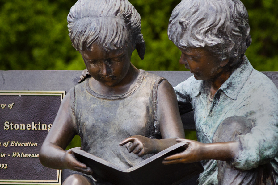 A statue of two children reading together.