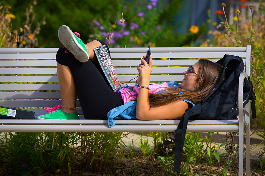 UW-Whitewater student relaxes on a bench outside McGraw Hall on the UW-Whitewater campus.