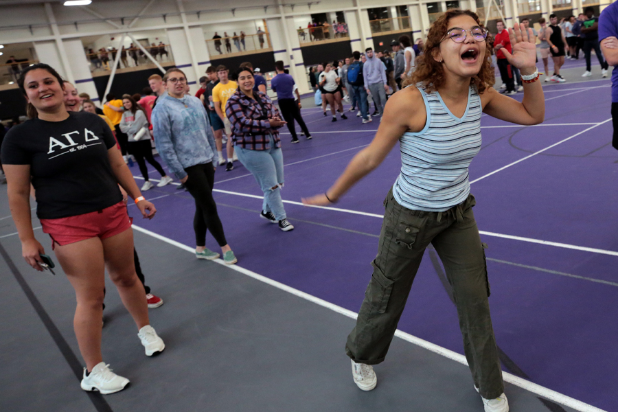 A student cups her mouth as she yells during a relay race in the fieldhouse.