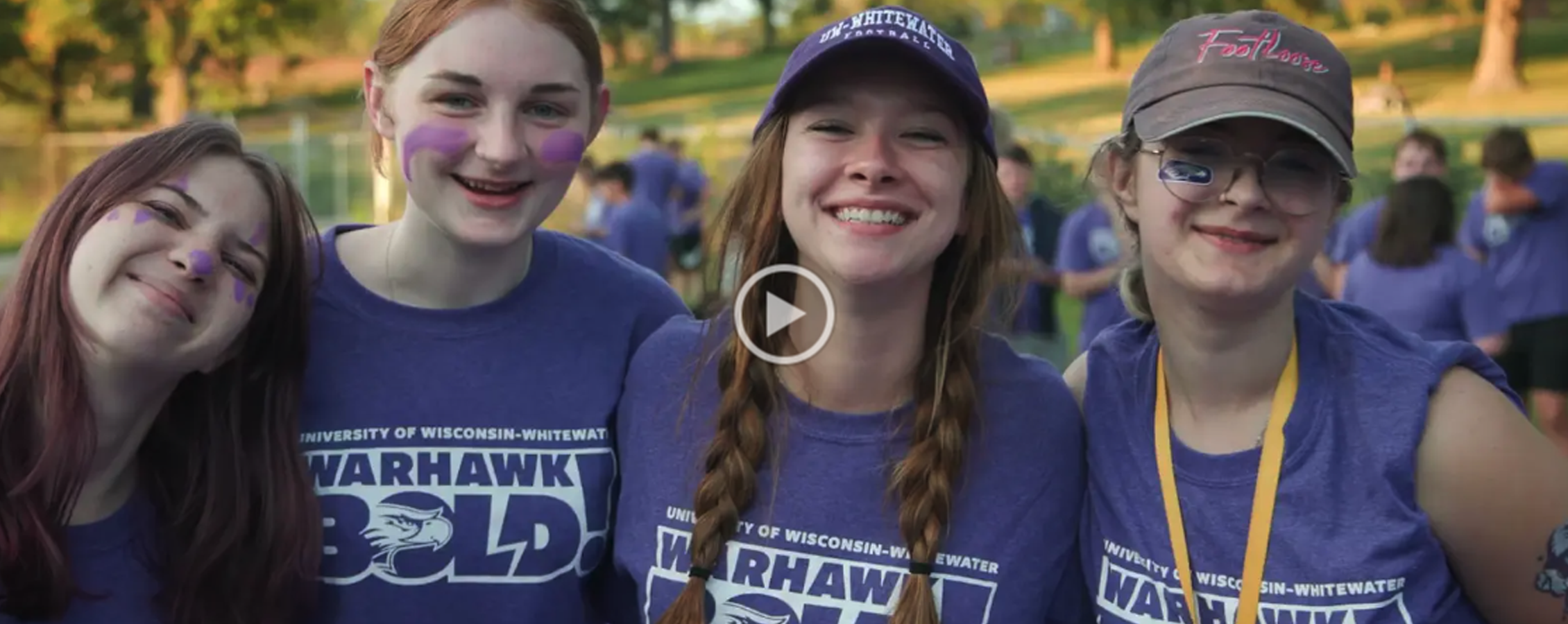 Four students in purple shirts smile at the camera with their arms around each other.