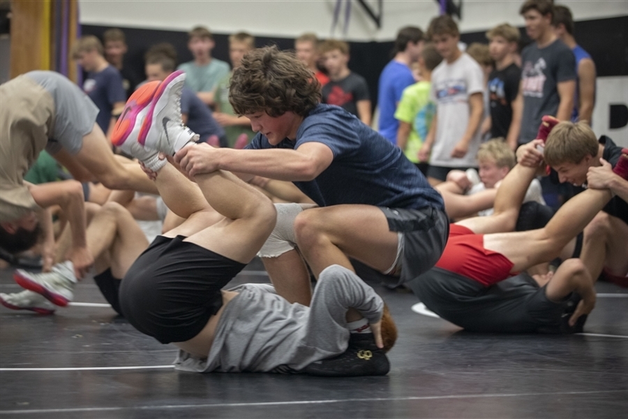 Students wrestling in a gym on a mat