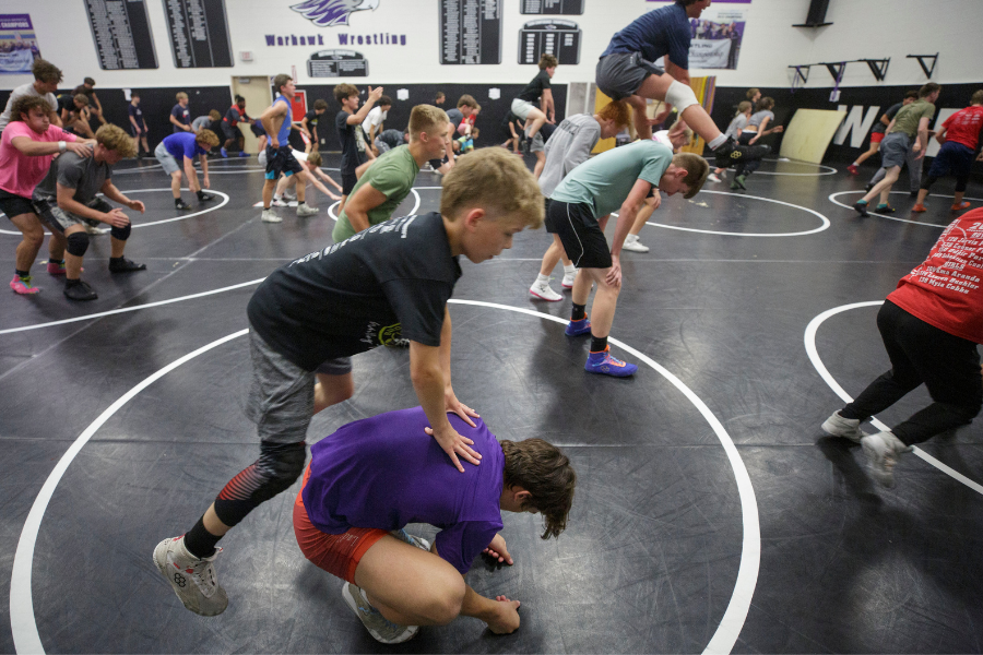 Students wrestling in a gym on a mat
