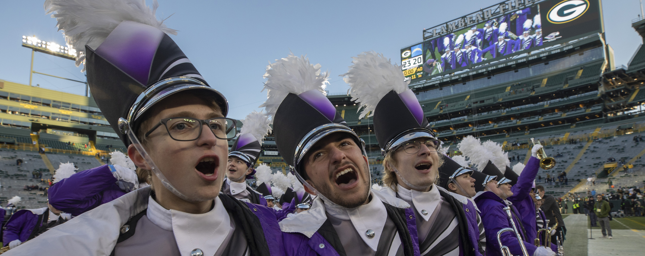 Warhawk Marching band stands in a line and sings on Lambeau Field.