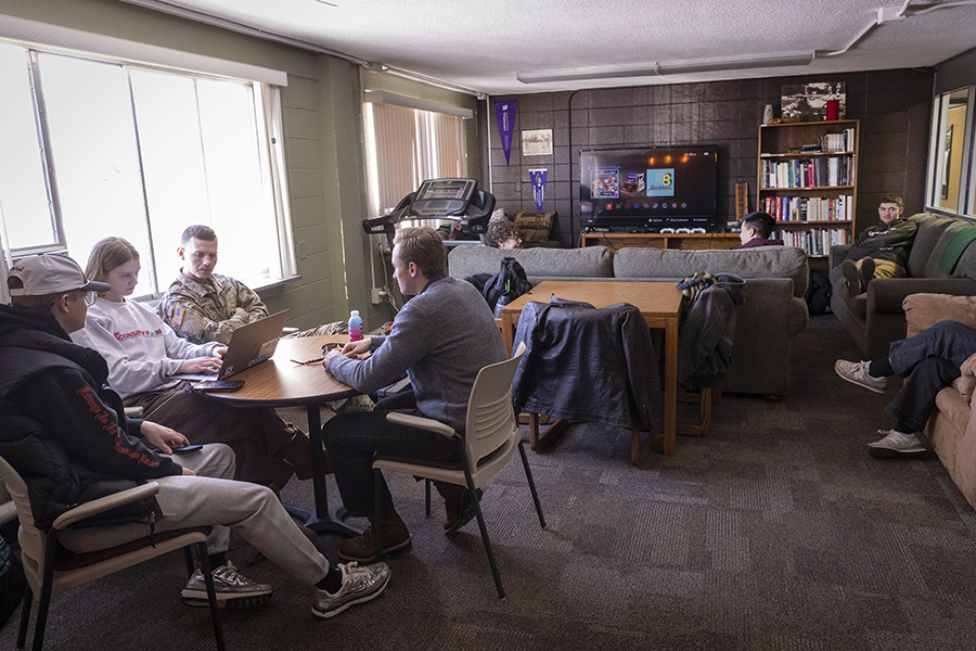 An interior space with a purple wall and a white eagle with several chairs and flags hanging in the background.
