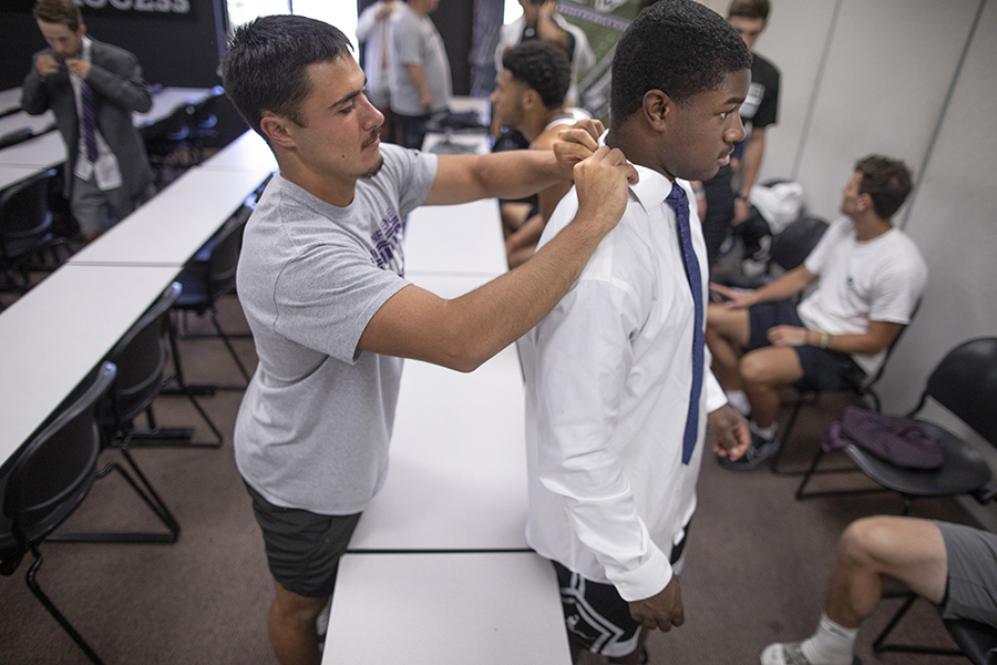 A person helps another person fix their collar and tie.