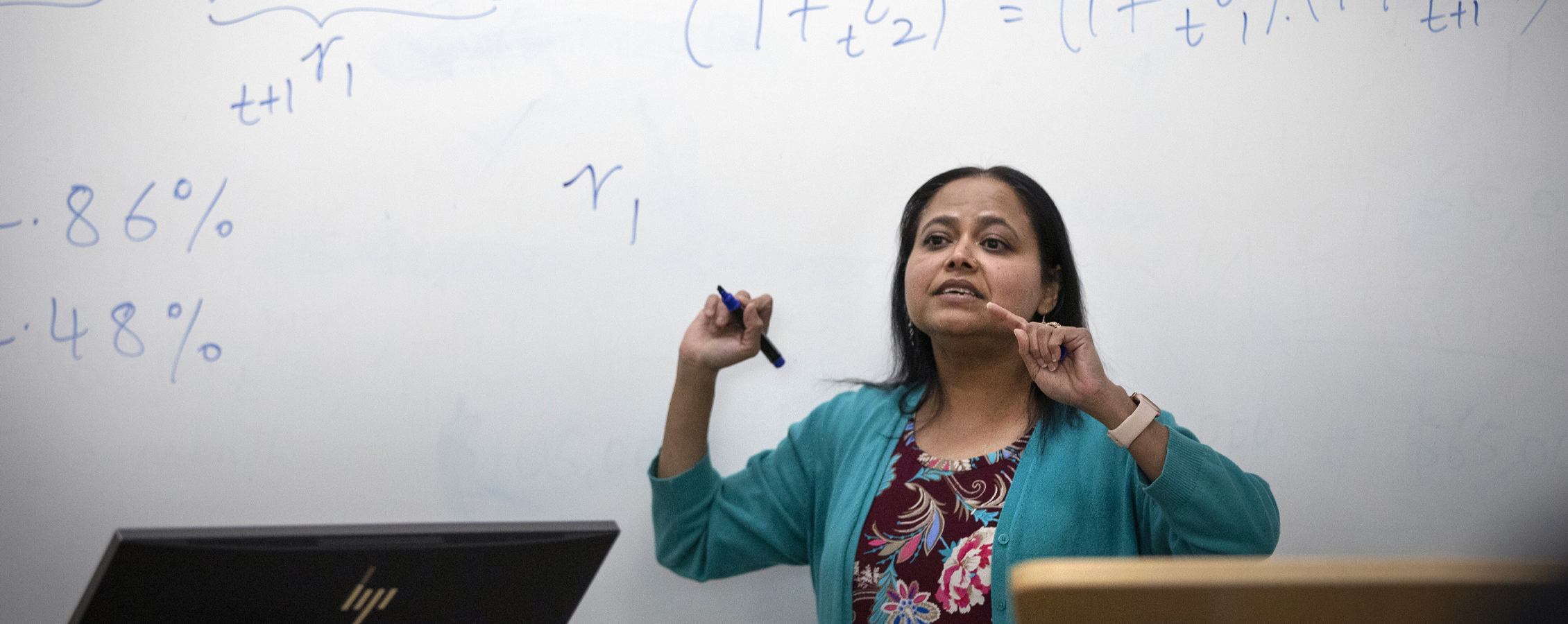 A faculty member teaches in front of a whiteboard.