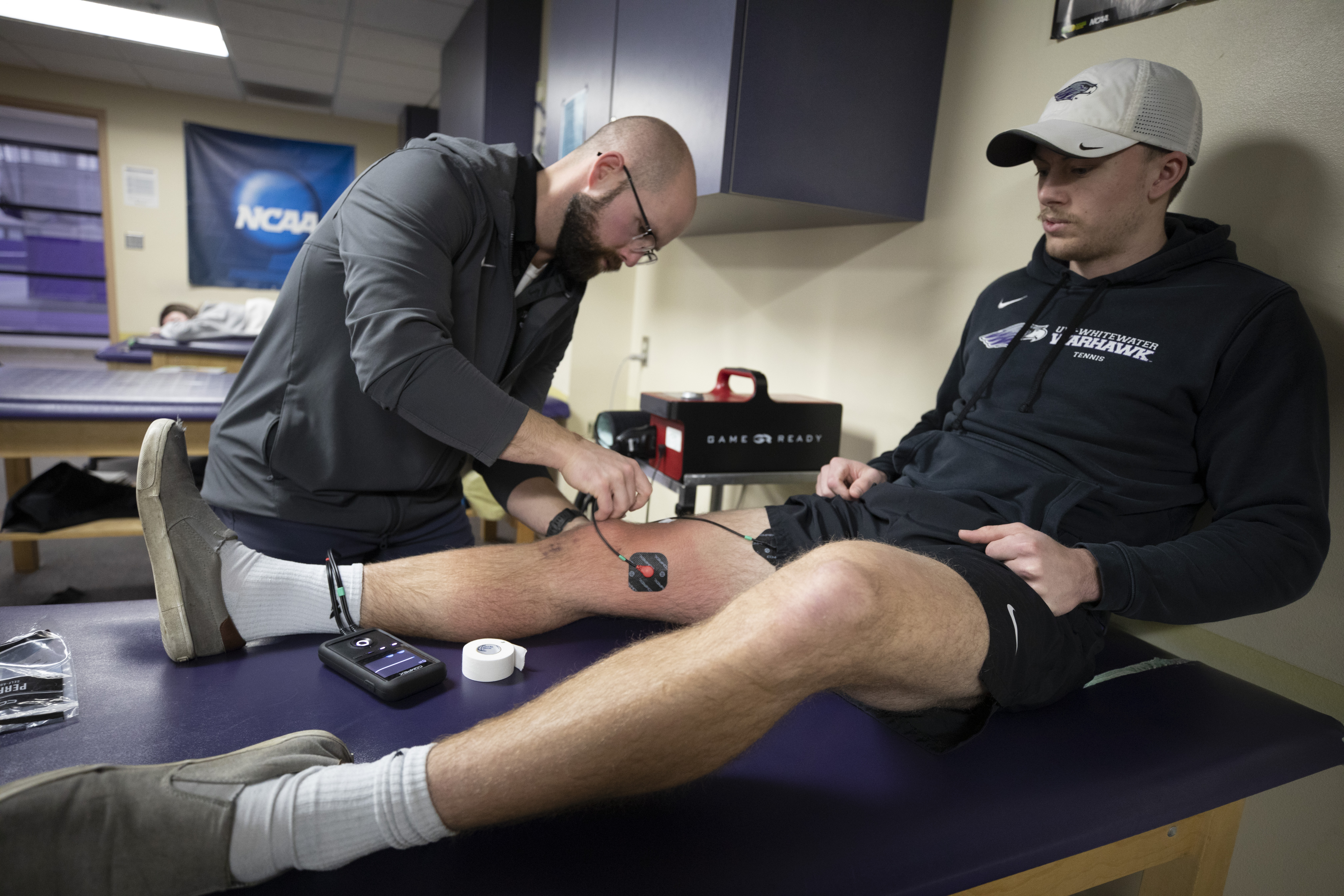 Trainer putting electrodes on leg