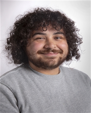 pacific islander man in early twenties with curly dark hair and dark eyes smiling