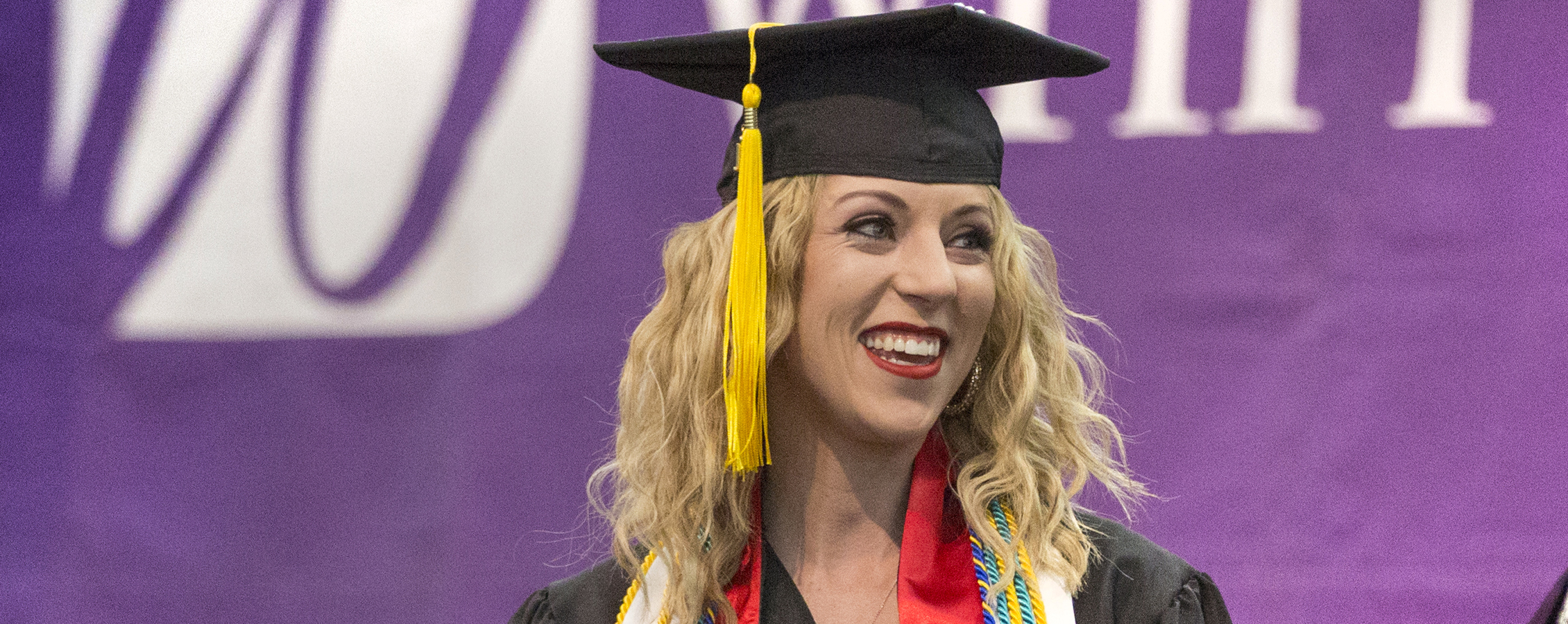 An international student smiles at graduation.