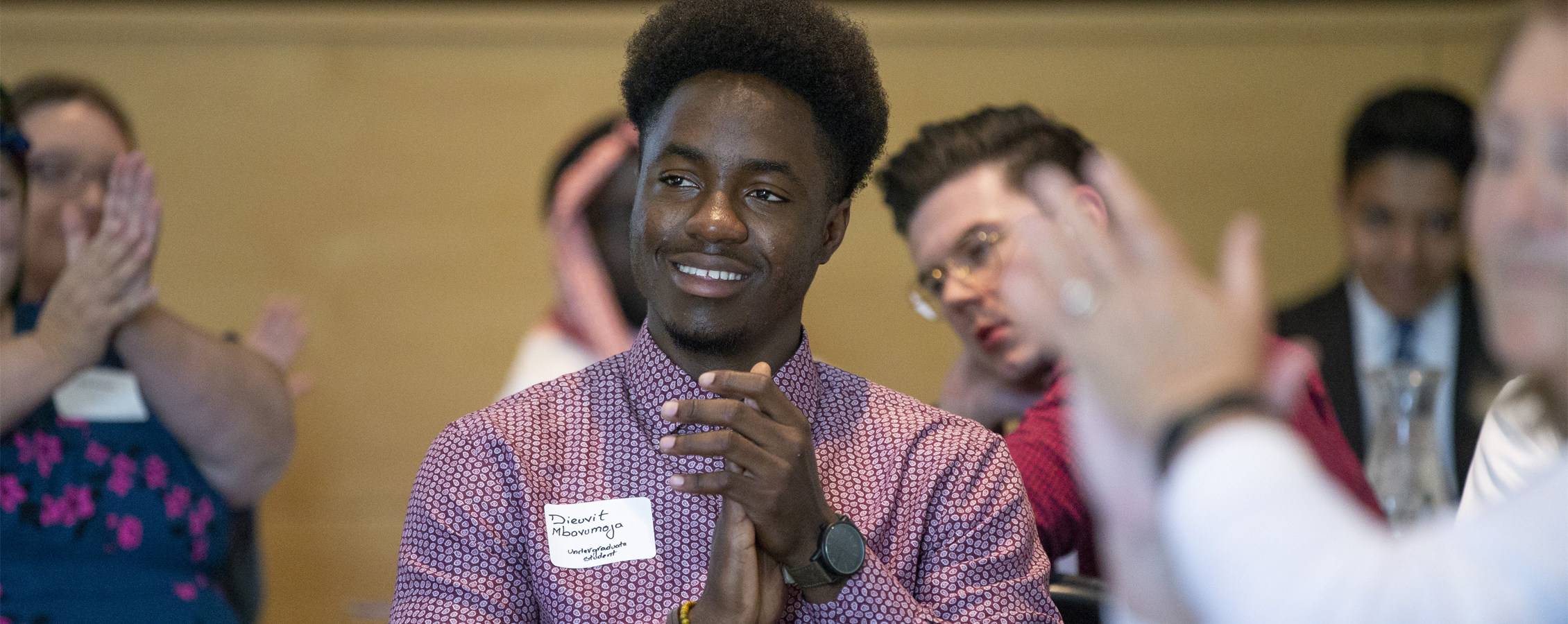 An international student claps during a campus event.