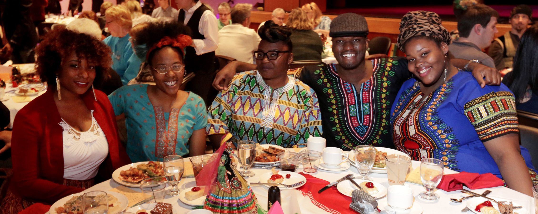 A group of international students group together at a banquet table and pose for a photo.