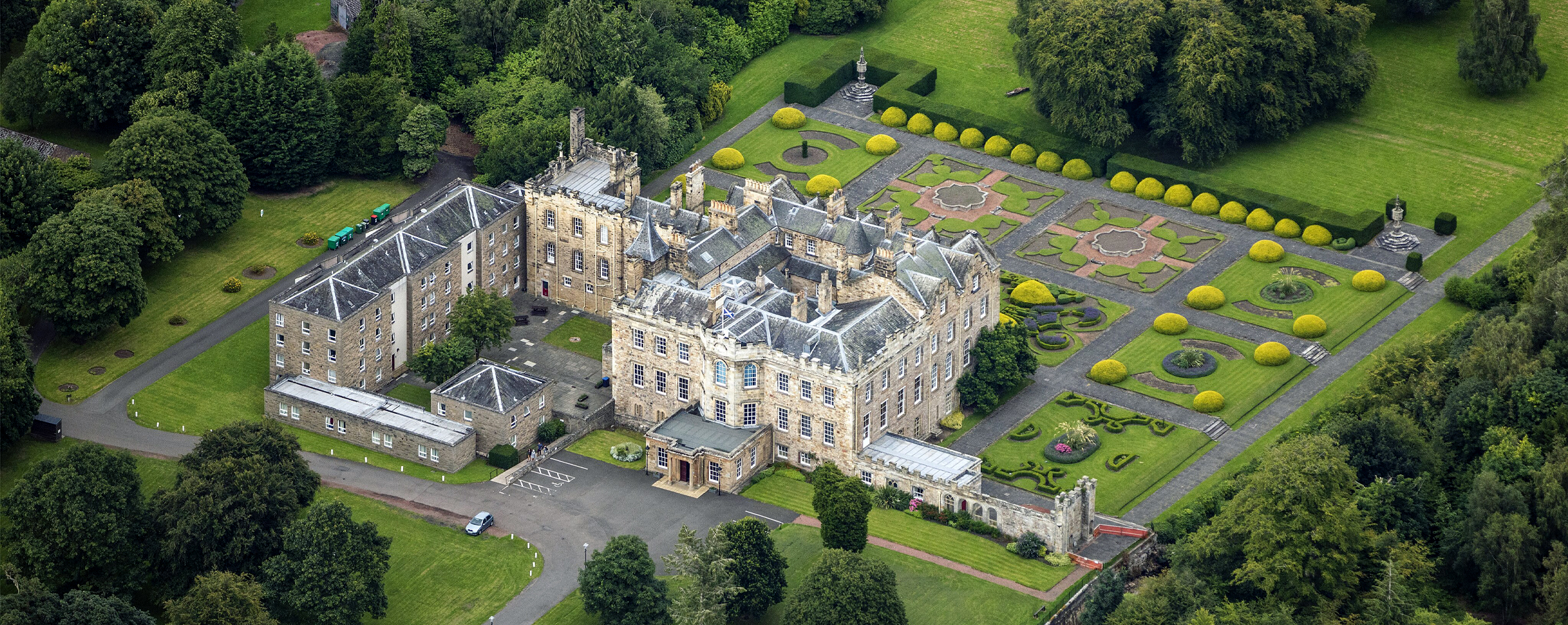 A photo of Dalkeith Palace, a sprawling three story castle with a stone exterior.