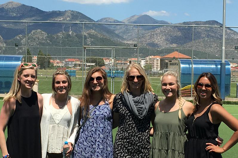 Student athletes stand together and smile at the camera with mountains in the background.