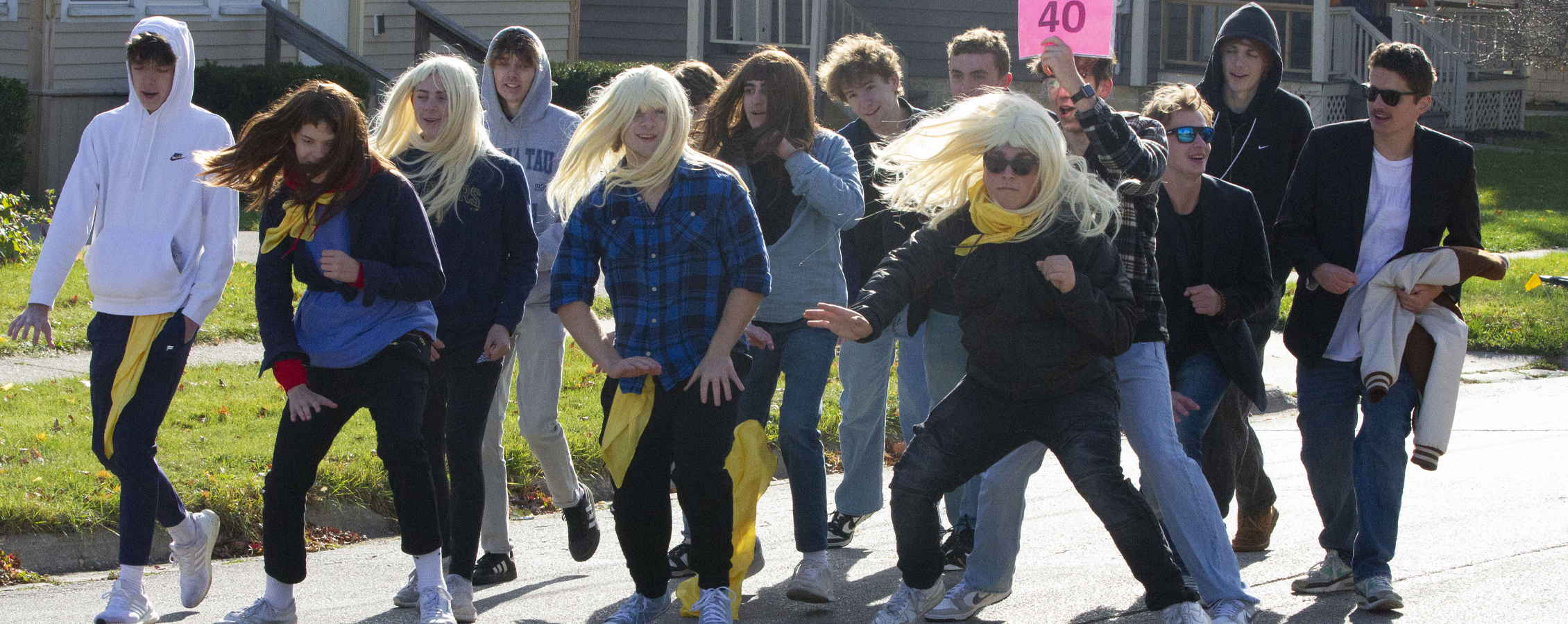 Several people march down the road during the parade wearing wigs.