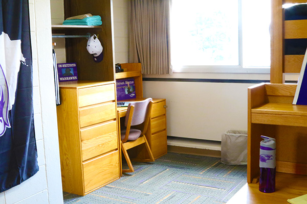 A dorm room where the beds are bunked, there is more free floor space in the room with this furniture arrangement.