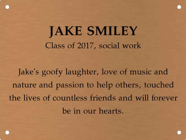 Copper memory wall plate that says Jake Smiley. Class of 2017, social work. Jake's goofy laugh, love of music and nature and passion to help others touched the lives of countless friends and will forever be in our hearts.