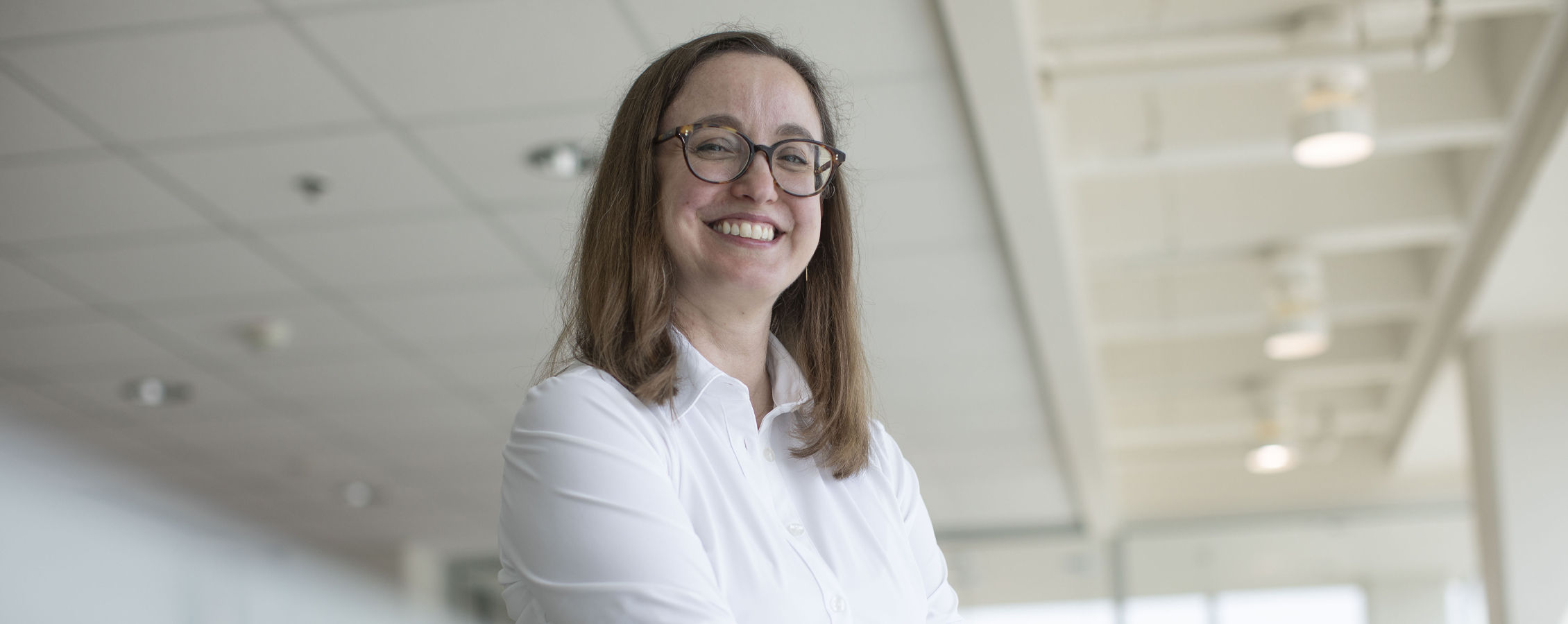 Anneke Lisberg wears a white shirt and smiles at the camera.