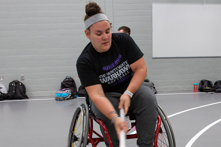 A student in a wheelchair demonstrates a game they have created with a stick and a ball.