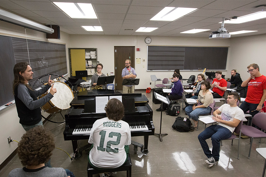 Jeff Herriott stands in front of his class of students with instruments in their hands.