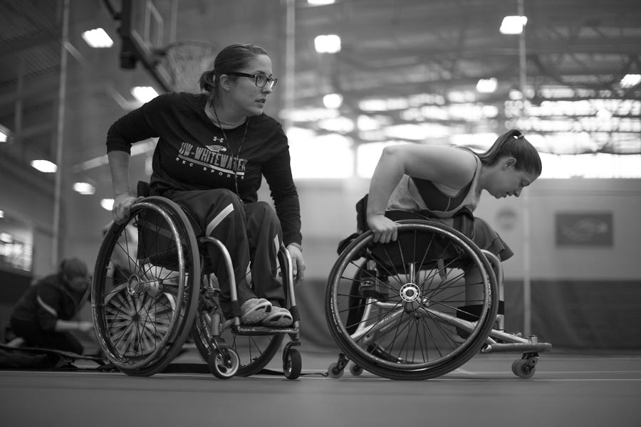 A black and white photo of wheelchair basketball athletes on the court.